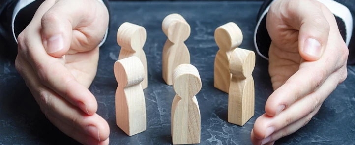 Executives Close Protection Services - Photo of small wooden men standing in a circle and two hands surrounding them for protection