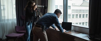 Picture of private investigators conducting covert surveillance through a window in a building.